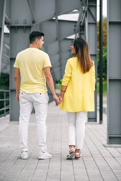 Όμορφη νεαρό ζευγάρι σε φωτεινά ρούχα κρατώντας τα χέρια — Φωτογραφία Αρχείου