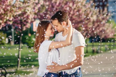 Sakura ağaçlar çiçek bahçesinde yakınındaki çift sarılmak. Aşık çift harcamak zaman arka plan üzerinde çiçekler bahar bahçe içinde yakın çekim. Tutku ve aşk kavramı.