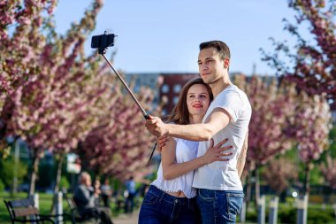 Tutku ve aşk kavramı. Erkek ve kadın bahar gününde çiçek açan bahçede öpüşme. Çift sakura ağaçlar sarılmak. Aşık çift bahar bahçede vakit.