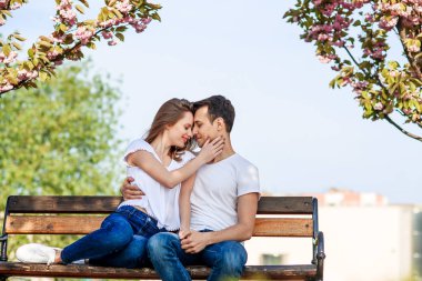 Sakura ağaçlar çiçek bahçesinde yakınındaki çift sarılmak. Aşık çift harcamak zaman arka plan üzerinde çiçekler bahar bahçe içinde yakın çekim. Tutku ve aşk kavramı.