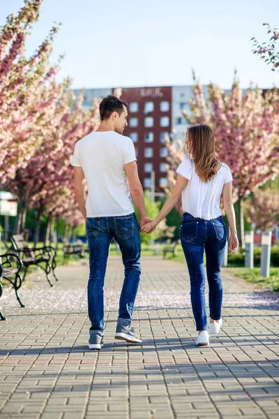 情熱と愛の概念。男と女の春の日に咲く庭のキスします。カップルは、桜の木の近く抱擁します。愛のカップルは、春の庭の時間を過ごす. — ストック写真
