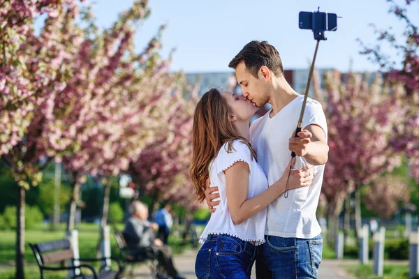 情熱と愛の概念。男と女の春の日に咲く庭のキスします。カップルは、桜の木の近く抱擁します。愛のカップルは、春の庭の時間を過ごす. — ストック写真