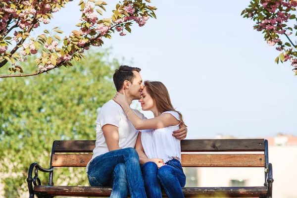Un par de abrazos cerca de árboles de sakura en el jardín floreciente. Pareja enamorada pasar tiempo en el jardín de primavera, flores en el fondo, de cerca. Concepto pasión y amor . — Foto de Stock