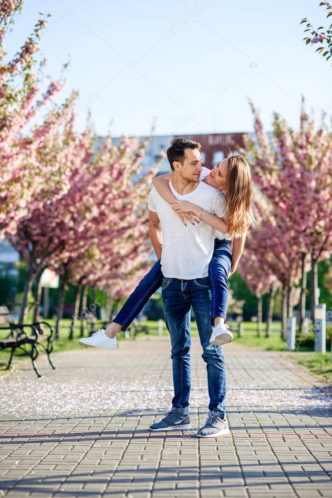 Passion and love concept. Man and woman kissing in blooming garden on spring day. Couple hugs near sakura trees. Couple in love spend time in spring garden.