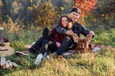 Genç bir çift ile onların evde beslenen hayvan köpek piknik üzerinde parkta oynarken. Kadın ve kadın ile köpek Parkı'nda eğlenmek.