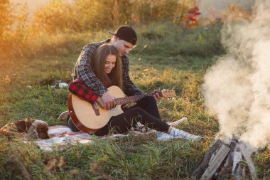 Genç adam onun güzel kız arkadaşı için gitar çalmaya. Bahar park piknik üzerinde dinlenme gitar ile mutlu çift.