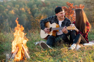 Genç adam onun güzel kız arkadaşı için gitar çalmaya. Bahar park piknik üzerinde dinlenme gitar ile mutlu çift.