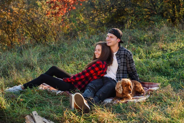 Ung man som spelar på gitarren för hans vackra flickvän. Lyckliga par med gitarr som vilar på picknick i vår park. — Stockfoto