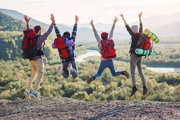 Group of five happy friends jumps at sunset time on background mountains — Stock Photo, Image