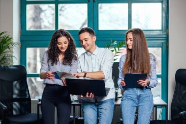 Genç Beyaz Mimarlar veya arka plan üzerinde büyük pencere ile şık modern ofis içinde belgili tanımlık laptop üzerinde yeni projesi için renk paletini kullanarak tasarımcılar.