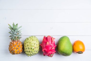Beyaz arka planda egzotik taze yaz meyveler. Ejderha meyve, ananas, Persimmon, Mango, Annona cherimola düz ücretsiz kopya alanı ile yatıyordu.