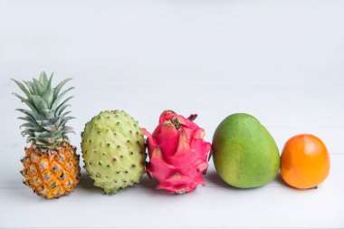 Beyaz arka planda egzotik taze yaz meyveler. Ejderha meyve, ananas, Persimmon, Mango, Annona cherimola düz ücretsiz kopya alanı ile yatıyordu.