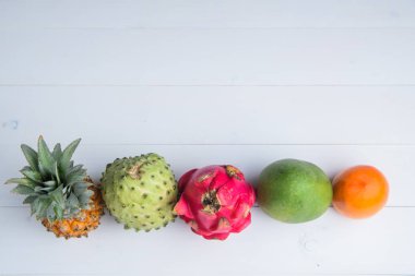 Beyaz arka planda egzotik taze yaz meyveler. Ejderha meyve, ananas, Persimmon, Mango, Annona cherimola düz ücretsiz kopya alanı ile yatıyordu.