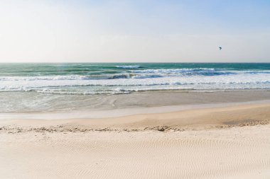 Sandy seashore with clear water and huge waves in the sea.