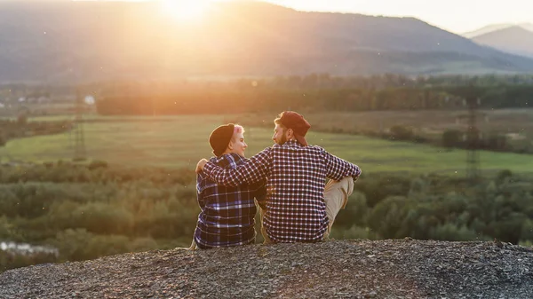 Giovane coppia seduta in cima alla montagna e guardarsi al tramonto.. Coppia gentile al tramonto romantico . — Foto Stock