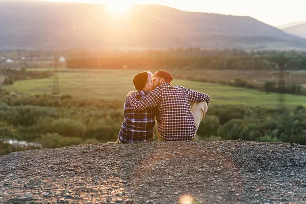 Beijo romântico ao pôr-do-sol. Homem hipster feliz no amor beija sua namorada no topo da montanha ao pôr do sol pano de fundo. Viagens e relações conceito . — Fotografia de Stock
