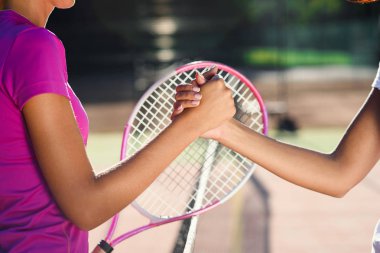 İki genç kadın tenisçi nin filenin üzerinde el sıkışırken çekilmiş yakın çekimi. Tenis turnuvası bittikten sonra dostça el sıkışma.
