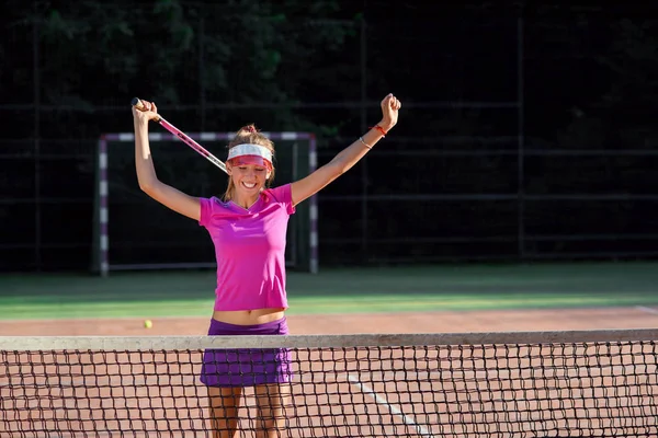 Bonne joueuse de tennis sautant près du filet et riant, célébrant sa victoire dans un match de tennis. Sport, concept de santé . — Photo