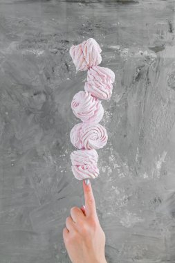 Kadın elinde marshmallow dengeleme. arka plan beton duvara karşı pembe ev yapımı marshmallow çok.