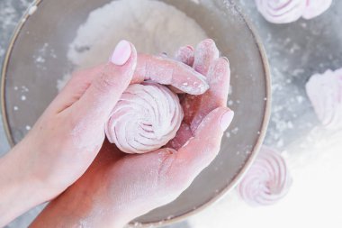 Yakın kadın elleri şeker pudraile plaka bir arka plan karşı taze hazırlanmış ev yapımı marshmallow tutar.