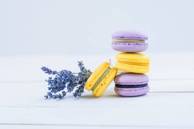 Lezzetli mor ve sarı makarnalar ve beyaz ahşap arka plan üzerinde kokulu lavanta dalı.