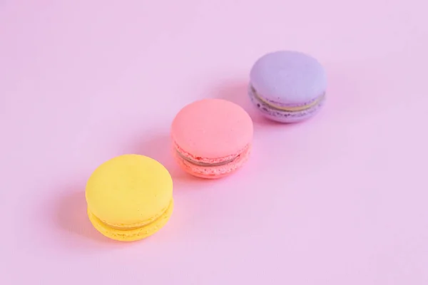 Tasty violet, pink and yellow french macaron cakes on pink background. — Stock Photo, Image