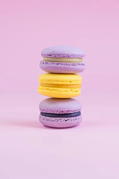 Sabrosos pasteles de macarón francés violeta y amarillo sobre fondo amarillo . — Foto de Stock