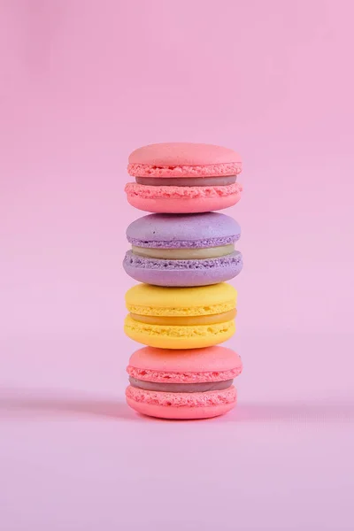 Tasty violet, pink and yellow french macaron cakes on pink background.