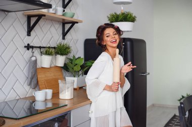 Güzel kız sabah rahat evde mutfak silindiri ile beyaz bornoz giymiş.