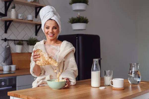 Kafasına bornoz ve havlu içinde büyüleyici kadın gevreği ve süt ile sağlıklı bir kahvaltı hazırlar. Kız sabah şık rahat mutfakta bir kahvaltı var.