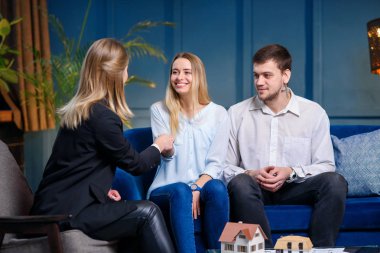 Şık genç kadın emlakçı yeni daire, mutlu kafkas çift için ev anahtar veren.