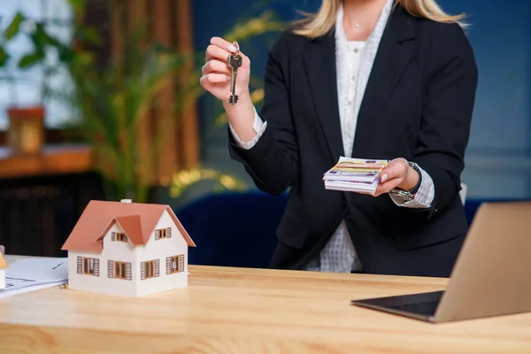 Real estate agent with key from house and money in the hands. — Stock Photo, Image