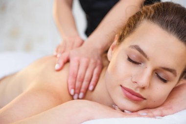 Spa salonunda masaj sırasında yakışıklı rahatlatıcı kadın.