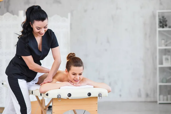 Jovem feliz relaxando durante a massagem nas costas no salão de spa . — Fotografia de Stock