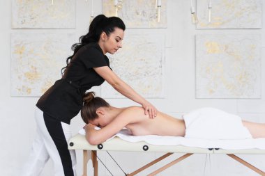 Odaklı beyaz masör Spa salonunda genç kadına rahatlatıcı masaj yapma.