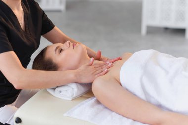 Spa salonunda masaj masasında yatarken masaj yaptıran mutlu genç kadın.