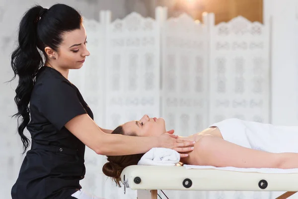 Young professional masseur making massage for sleepy caucasian woman on the white room background. — Stock Photo, Image