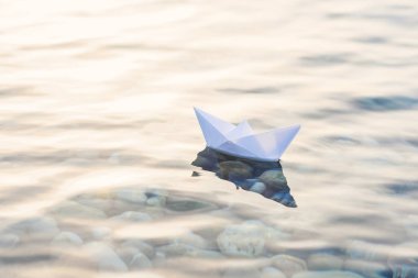 Mavi derin suda origami beyaz kağıt tekne.
