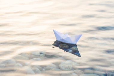 Mavi derin suda origami beyaz kağıt tekne.