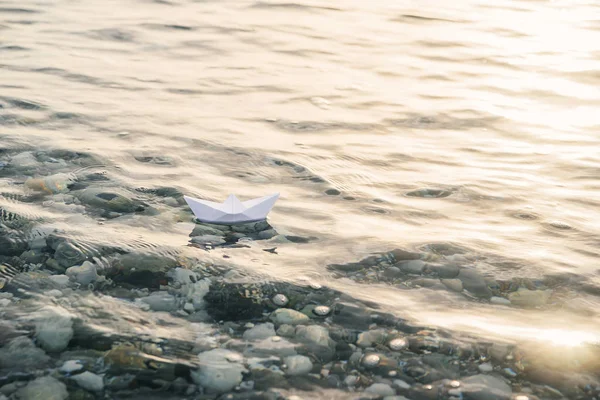 Alone paper boat floats in waves on the water.