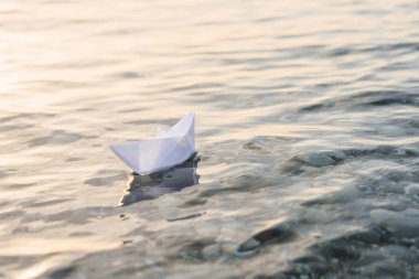 Mavi derin suda origami beyaz kağıt tekne.