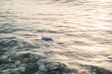 Mavi su yüzeyinde deniz üzerinde kağıt tekne yelken.
