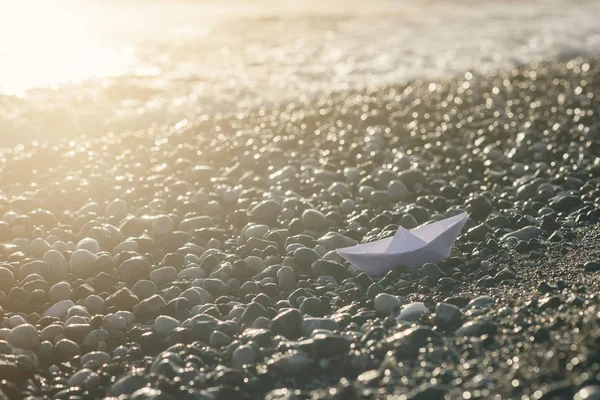 Łódź papierowa leży na wybrzeżu o wschodzie słońca. — Zdjęcie stockowe