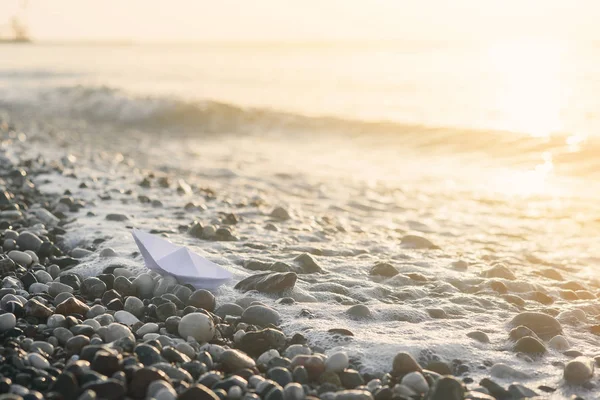 Barco de papel encontra-se à beira-mar ao nascer do sol . — Fotografia de Stock