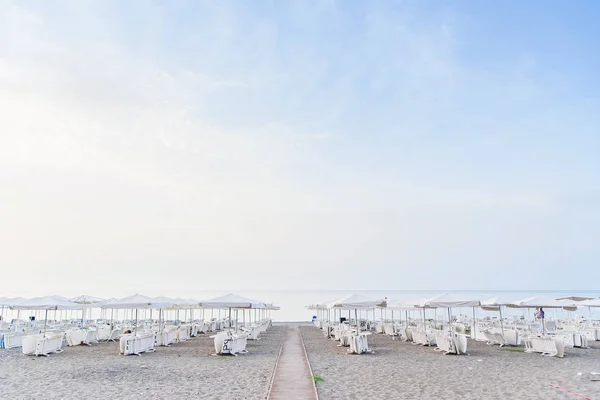 Escena idílica de tumbonas bajo un paraguas en una playa limpia bajo el sol caliente de la tarde . — Foto de Stock