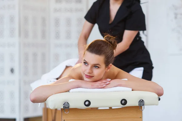 Handsome young woman during massage on the back in spa salon. — Stock Photo, Image