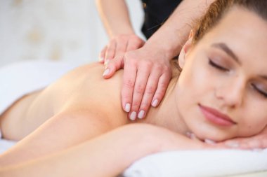 Spa salonunda masaj sırasında yakışıklı rahatlatıcı kadın.