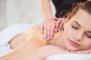 Spa salonunda masaj sırasında yakışıklı rahatlatıcı kadın.