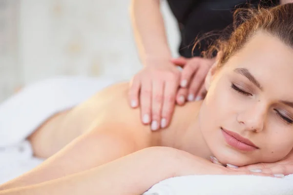 Красивая расслабляющая женщина во время массажа в спа салоне . — стоковое фото