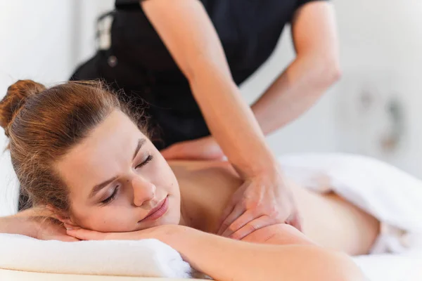Женские руки массажистки делают массаж молодой женщине в спа-центре . — стоковое фото